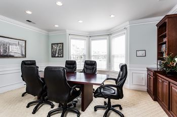 A conference room with a wooden table and black chairs